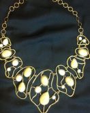 Maxi colar dourado com pedrinhas bege.